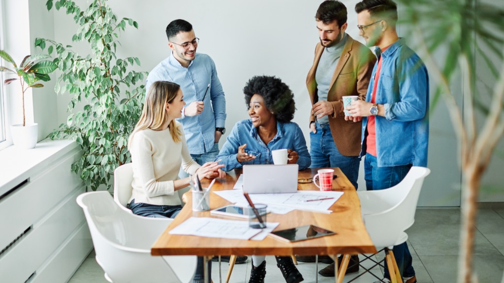 A group of employees working around a table and smiling.